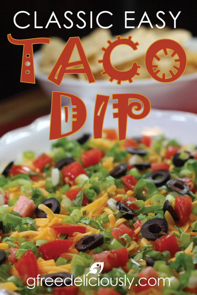 Pinterest image of Classic Easy Taco Dip on a serving plate topped with shredded cheddar cheese, lettuce, roma tomatoes, sliced black olives, and green onions.