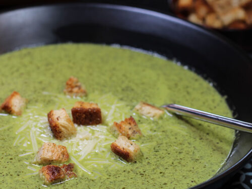 closeup of creamy spinach soup in a black bowl