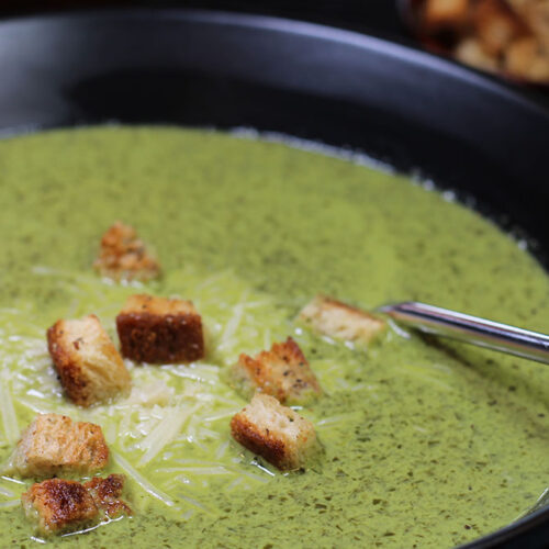 closeup of creamy spinach soup in a black bowl