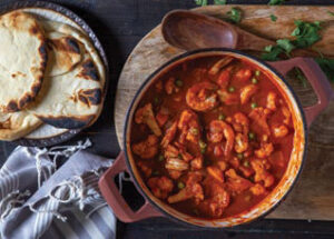 Berbere Shrimp Curry in a pot shown with flatbread on a plate