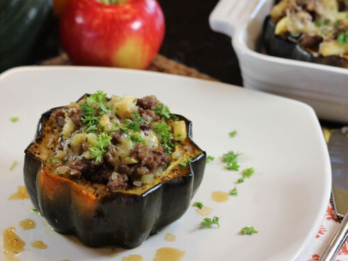 one serving (one half) stuffed acorn squash on a plate at table placesetting