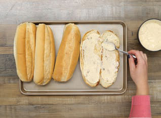 adding a smear of remoulade sauce to the baguettes