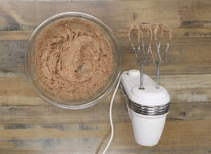 In a separate bowl, melt the milk chocolate by microwaving for 15-second intervals until melted and smooth. Let the chocolate cool slightly, add the butter and both sugars, beating until light and fluffy