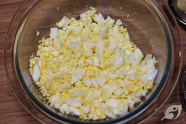 Egg salad step 1 - Add hard-boiled and peeled eggs to a medium-size mixing bowl and chop. Mix in the butter just until combined.