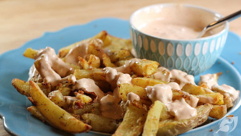 Closeup of fries with a drizzle of our favorite dipping sauce with bowl of sauce in the background.