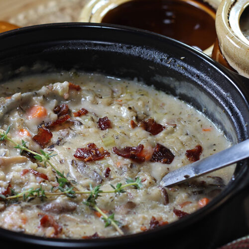 Pot of Creamy Wild Rice & Mushroom Soup with filled bowl in the background