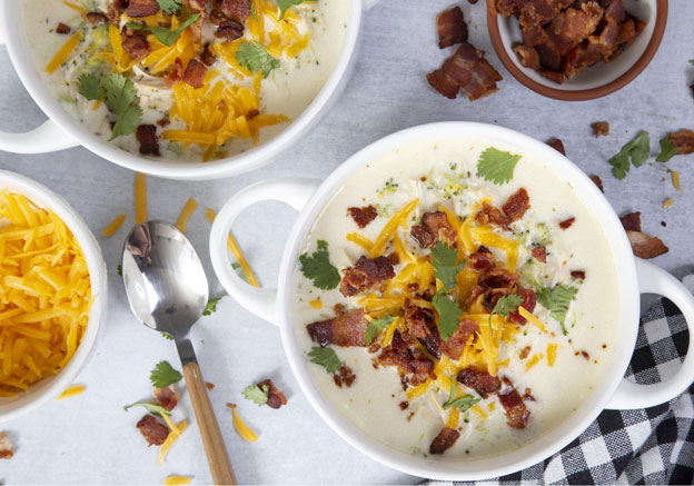Two bowls of Chicken Bacon Ranch Soup with extra cheddar cheese and bacon in bowls on the side