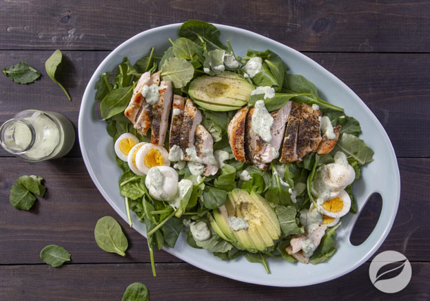 Green Goddess Chicken Cobb Salad on a flat dish with green goddess dressing on the side