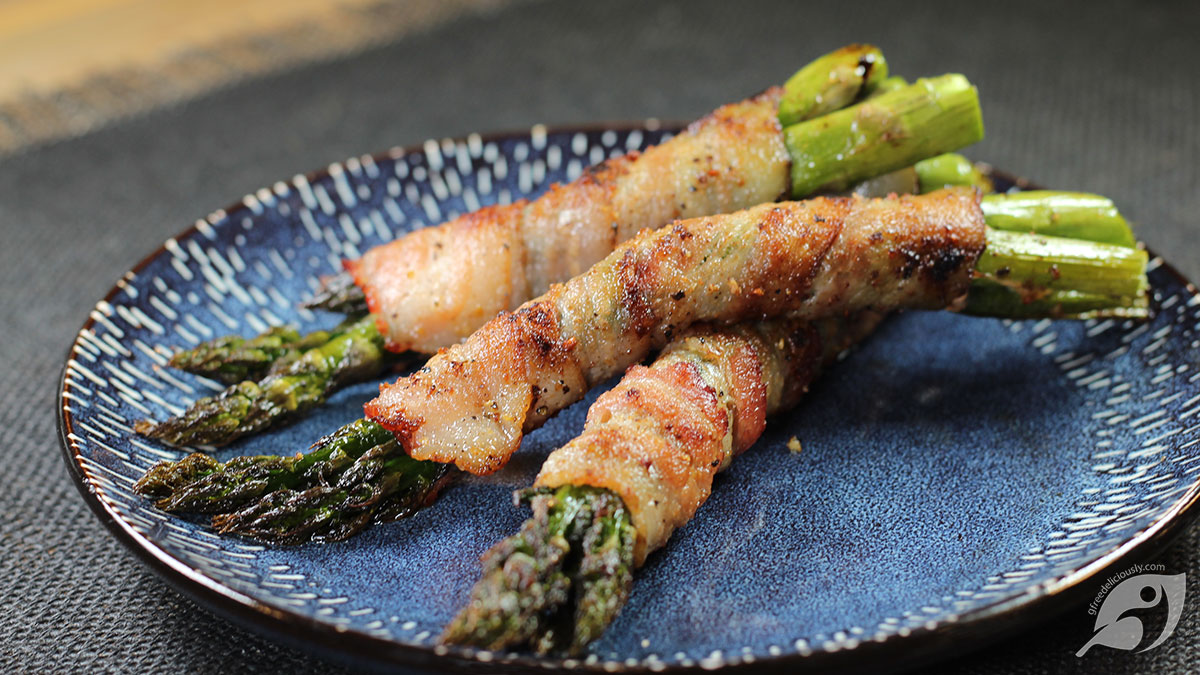 Grilled Bacon Wrapped Asparagus bundles on a blue plate.