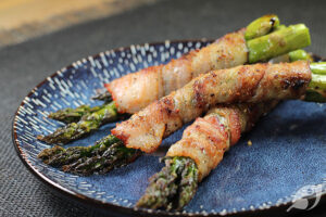 Grilled Bacon Wrapped Asparagus bundles on a blue plate.