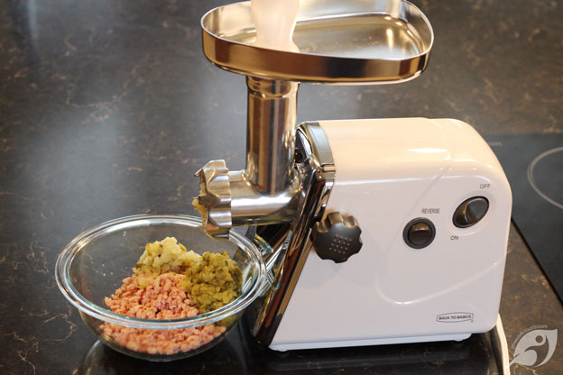Ham, pickles, and onion ground in a bowl. Showing an electric meat grinder.