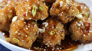 Close-up of Baked Orange Chicken Meatballs on a plate with chopsticks.