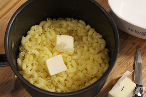 Cooked elbow macaroni in a pan with butter.