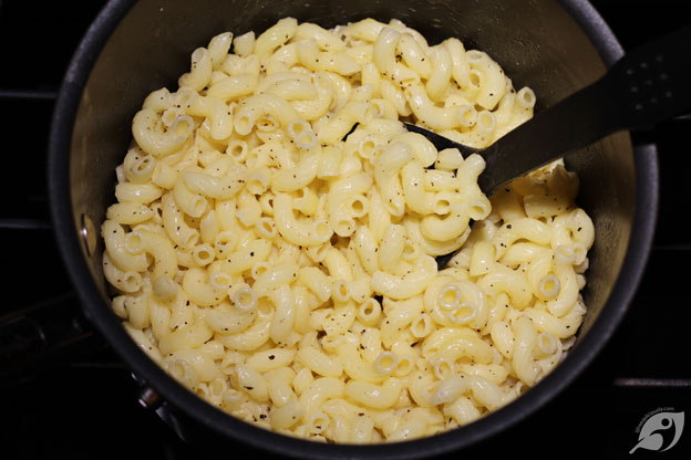 Cooked elbow macaroni in a pan with butter, salt, and pepper.