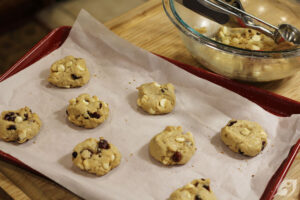 Step 8 - Scoop the dough using a 1 ½ tablespoon (medium-size) cookie scoop. Place cookies 2-3 inches apart on prepared cookie sheets. If desired, top with additional white chocolate chips and cranberries. Lightly press down on the top of each cookie to flatten slightly, then brush each cookie with a bit of milk before baking to help in browning.