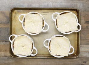 Step 4 - Butternut Squash & Mushroom Chicken (or Turkey) Pot Pies: Cut puff pastry into four squares, placing one square on top of each of the ramekins. Using a sharp knife, cut a few slits in the puff pastry for venting.