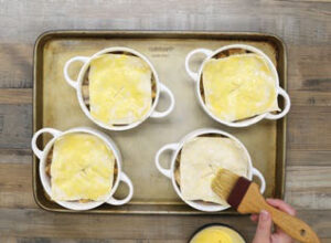 Step 5 - Butternut Squash & Mushroom Chicken (or Turkey) Pot Pies: Whisk together the egg yolk and the remaining 1 tablespoon cream. Brush the puff pastry with the yolk mixture. Place ramekins on a sturdy sheet pan and bake for about 20 minutes or until the puff pastry is golden brown and crisp around the edges.