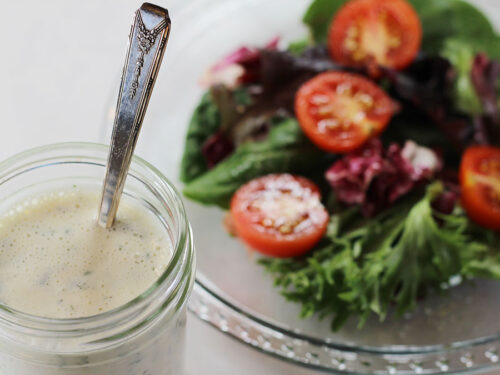 Homestyle Ranch Dressing & Dip Mix in a jar with a fresh green salad on a plate in the background.