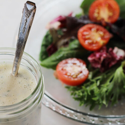 Homestyle Ranch Dressing & Dip Mix in a jar with a fresh green salad on a plate in the background.