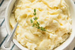 Drain the potatoes and garlic and mash together. Stir in the hot milk, season to taste with salt and pepper, and add the 2 tablespoons butter (less if desired) or oil. Top with remaining 1 tablespoon butter pat, serve immediately.