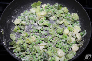 Two tablespoons of flour added to eeks, peas, and butter in a 9-inch skillet.