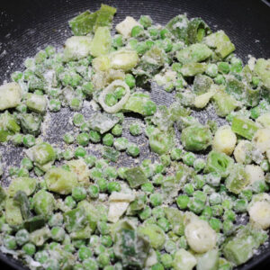 Two tablespoons of flour added to eeks, peas, and butter in a 9-inch skillet.