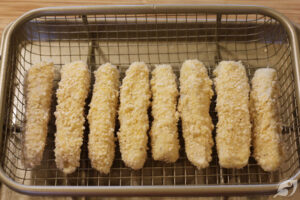 When all the fish portions are done. Lightly spray the top of the fish sticks with the coconut oil spray.