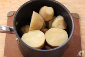 Scrub and remove any bad spots from the potatoes and cut them into large chunks. Next, parboil the potatoes by placing them in a large pot. Cover them with 1-inch cold water, then bring them to a boil over high heat. Immediately reduce the heat to medium to simmer for 6-7 minutes (the potatoes will only be halfway cooked). Drain and rinse with cold water until easy to handle.
