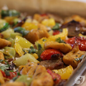 Closeup of roasted gnocchi, sausage and veggies on a sheet pan.