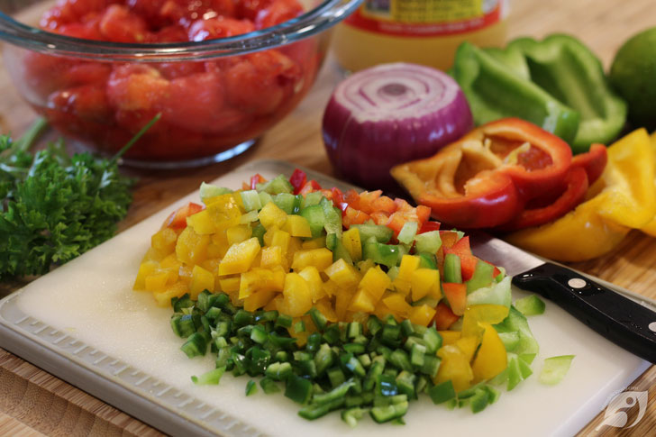Coarsely chop the tomatoes, sweet peppers, onion, and parsley, adding each to a large bowl. Add the minced jalapeño to the bowl, then the minced garlic, one tablespoon of the vinegar, kosher salt, and the lime juice. Stir lightly to combine.