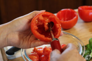 Remove the vines and stems. Then wash the tomatoes, removing the upper section of the tomato (about one-quarter inch or so below the stem area) by slicing horizontally around the top, and discard. Once the top is removed, use a melon baller (or a spoon) to scoop out the inside flesh and seeds (discard), being careful not to poke through the walls of the tomato.