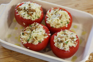 Using a large spoon, fill the empty tomatoes with the stuffing. Sprinkle the filled tomatoes with the remaining mozzarella cheese and drizzle a small amount of olive oil over the top of each one.