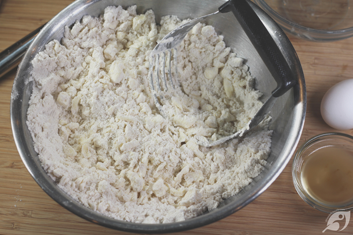Work the pats into the flour mixture with a pastry cutter (dough blender or using two forks) until it is crumbly, with some larger pea-size chunks of butter remaining.