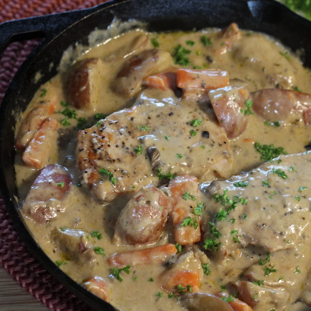 One Skillet Pork Chops and Veggies Instagram Share Image 1080x1080px - closeup photo of pork chops and veggies in gravy in a cast iron skillet.