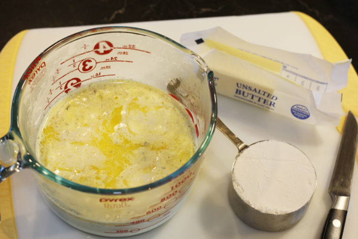 Photo shows 1 ½ cups of the scalded milk ladeled into a large glass measuring cup. The unsalted butter is adde to the cup with the milk to melt.