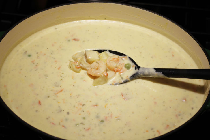 The Dutch oven is shown with the seafood added. the chowder is thickened.