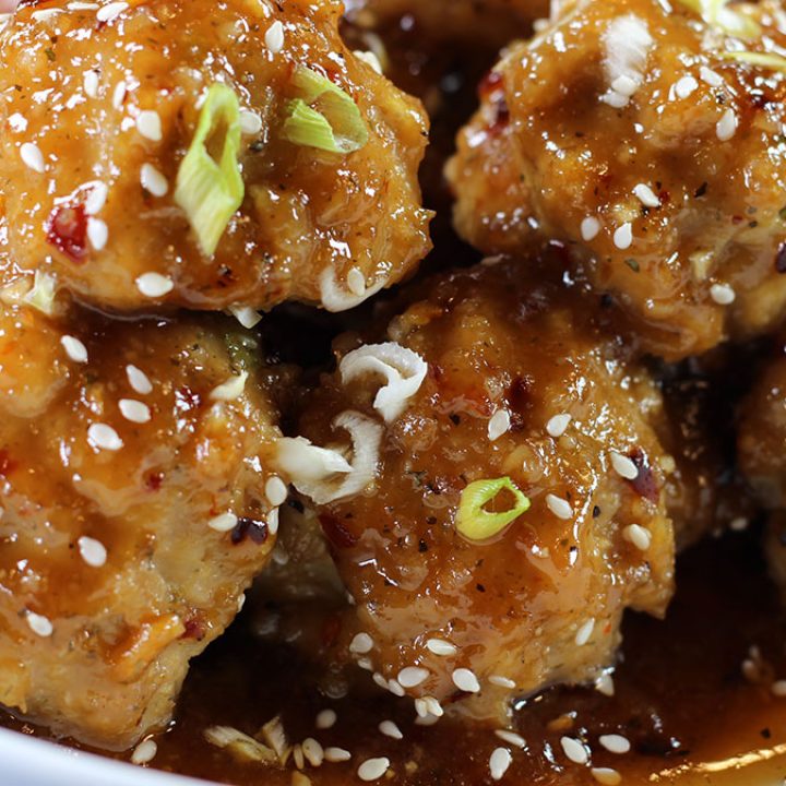 Close-up of Baked Orange Chicken Meatballs on a plate with chopsticks.