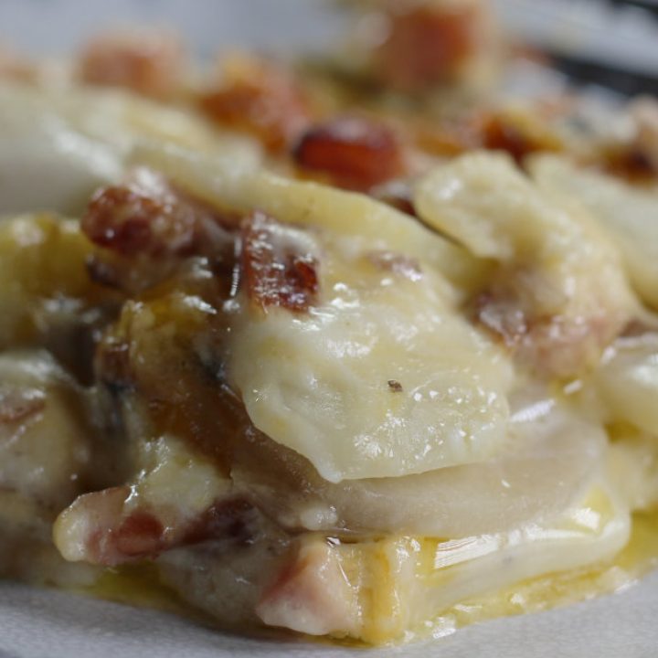Closeup photo of Cheesy Scalloped Potatoes with Ham and Mushrooms with a fork in the background